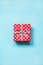 Top view of a red dotted gift box tied with silver bow over blue background.