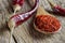 Top view red dried crushed hot chili peppers and chili flakes or powder in wooden spoon on wooden rustic background