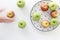 Top view of Red and green apples in white plate with black triangles pattern and apples with moving hand on white background