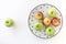 Top view of Red and green apples in white plate with black triangles pattern and green apple on white background