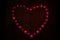 Top view of red heart of burning candles on black background in darkness. Valentine`s Day