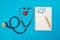 Top view of red heart stethoscope pill notepad on isolated blue background. Medical concept