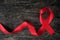 Top view of red ribbon on aged dark wood background. AIDS, HIV, heart disease and stroke awareness concept. Testing and Screening