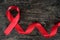 Top view of red ribbon on aged dark wood background. AIDS, HIV, heart disease and stroke awareness concept. Testing and Screening