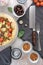 Top view of a restaurant table with delicious pizza, beer, brown olives, and spices