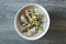 Top view of rice congee in white bowl on wooden table.