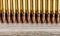 Top view of rifle full metal jacket bullets in a row on wooden background with copy space