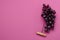 Top view of ripe grapes and handle corkscrew on the empty dark pink background