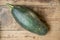 Top view of a ripe large zucchini plucked from the garden bed and lying on a wooden surface. Selective focus