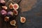 Top view of ripe whole and cut delicious figs and wooden brown cutting boards on stone background.