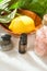 Top View Ripe Yellow Lemon in Wooden Bowl Essential Oil Bottle Green Palm Leaves Pink Himalayan Salt Balanced Zen Stones on Marble