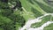 Top view of a river in the mountains on a sunny day. Top view wild river flowing between green mountains on a clear