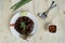 Top view of roasted meat on a white plate decorated with green groceries