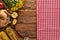 Top view of roasted turkey, grilled corn, apples and yellow wildflowers near red checkered napkin on wooden table.