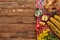 Top view of roasted turkey, grilled corn, apples and yellow wildflowers on red checkered napkin on wooden table.