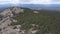 Top view of rock with tourists. Clip. Horizon of hilly terrain with cloudy sky. View of tourists climbing on rocky cliff