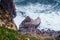 Top view of rocky beach seashore coastline surrounded by foamy waves, steep mountains cliffs covered with green grass.