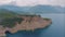 Top view of a rocky shore covered with green trees. Cave in the rock. The boat is near the shore. Aerial drone view