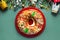 Top view of Roscon de reyes with cream and christmas ornaments on a red plate. Kings day concept spanish three kings cake.Typical