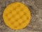 Top view of round fabric yellow pouf with buttons and squares. Gray carpet background