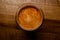 top view of round glass with foamy coffee drink on wooden table