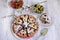 Top view on a round homemade pie with berries, herbal tea in a glass teapot, a piece of cake on a plate, gooseberries in a bowl