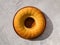 Top view of a round manna pie in a clay brown plate on a gray neutral background.