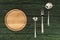 top view of round wooden cutting board and metallic kitchen utensils