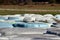 Top view of rows of large hay bales wrapped in blue and white nylon protection for preservation and storage left at local field