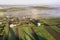 Top view of rural landscape on sunny spring day. Farm cottage, houses and barns on green and black fields. Drone photography