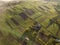 Top view of rural landscape on sunny spring day. Farm cottage, houses and barns on green and black fields. Drone photography