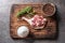 Top of view rustic wooden cutting board on dark background with duck thigh, herbs, spices and salt