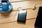 A top view of rustic wooden desk with black mobile phone, tablet, earphones and cup of coffee. Concept of workspace, home office,