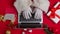 Top view Santa hands in white gloves are typing on keyboard laptop by red New Year decorated table. Santa Claus looks