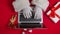 Top view Santa hands in white gloves typing on the keyboard by red New Year decorated table. Santa Claus works with