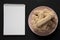 Top view, savoiardi or ladyfingers cookies on pink plate, blank notepad over black background, top view. Overhead, from above,