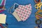 Top view of School supplies and cloth masks on blue wooden table