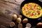 Top view scrambled eggs with greens, tomatoes and pumpkin seeds on brown wooden background with copy space and cinnamon eggs and