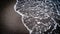 Top view of seawater splashing on a sandy beach in Santorini, Greece