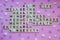 Top view of SELFCARE word on pink background with flowers. Minimalism creative crossword puzzle concept. Message of text