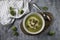 Top view of served brocoli creamy soup with cream and bread croutons on rustic table with spoon and fresh brocoli - photo with