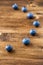 Top view of seven blue blueberries, the first one focused, the others in bokeh, on dark wooden board in vertical