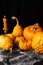 Top view of several orange halloween pumpkins and burning candle, on table with spiders and spider web, black background,