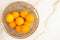 Top view of several oranges in a golden basket over a marble background