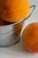 Top view of several peaches in metal bowl on white wooden background