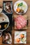 Top view of Shabu set including rare slices Wagyu A5 beef, Shabu shoyu and clear base, salmon, sushi and vegetables