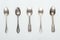 Top view of shiny aged silver empty spoons in row on white background.