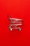 Top view of shopping trolley on red background. minimalistic photo of pushcart with some copy space around