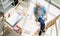 Top view shot of Caucasian old senior elderly retired white bearded male painter wearing glasses sitting on wooden chair drawing