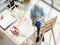 Top view shot of Caucasian old senior elderly retired white bearded male painter wearing glasses sitting on wooden chair drawing